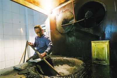 黄来乡在锅台边演示手工翻炒咖啡豆。