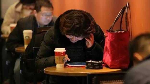 一位女士在中国上海的咖啡厅里用智能手机打电话