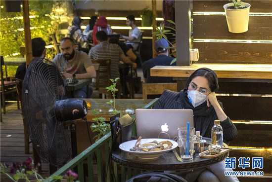 一名戴口罩的女子坐在一家咖啡馆内